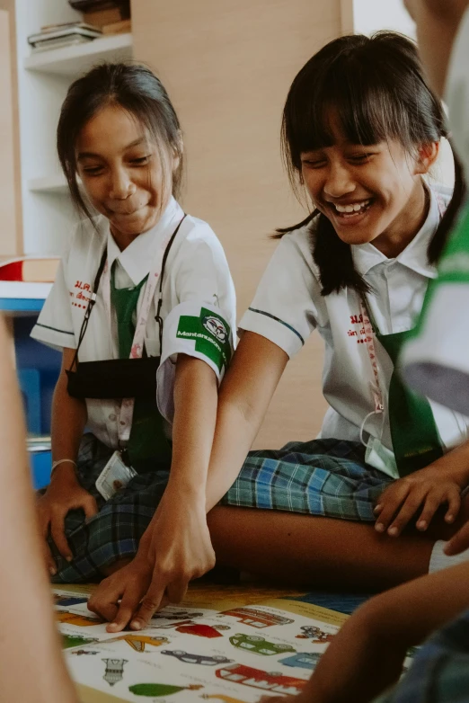 a group of girls sitting on the floor playing a game, pexels contest winner, happening, wearing school uniform, indonesia, smiling at each other, prosthetic limbs