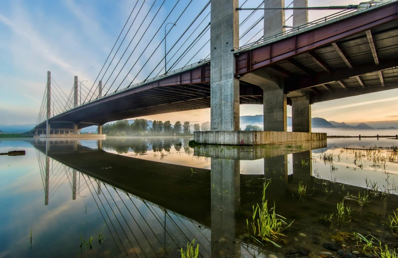 a bridge spanning over a body of water, by Joze Ciuha, pexels contest winner, modernism, british columbia, concrete pillars, clear reflection, 8k hdr morning light