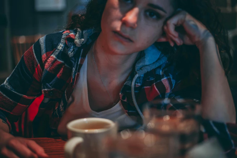 a woman sitting at a table with a cup of coffee, a picture, inspired by Elsa Bleda, trending on pexels, happening, portrait of depressed teen, mid night, 15081959 21121991 01012000 4k, grungy woman