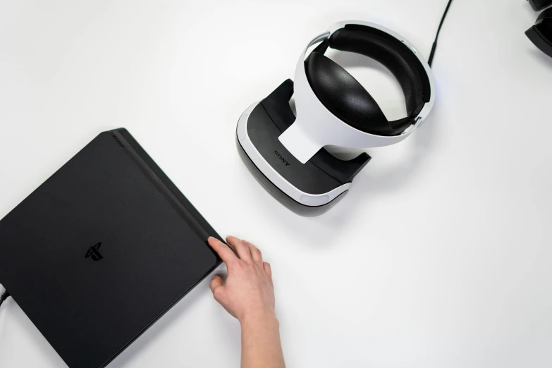 a person using a vr headset next to a laptop, for ps5, bottom - view, holding notebook, with black vines