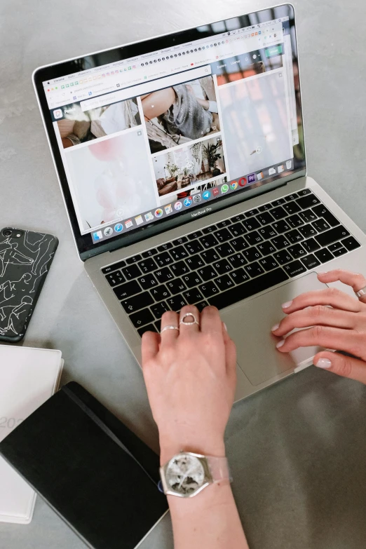 a woman sitting at a table using a laptop computer, a picture, by Julia Pishtar, trending on pexels, flatlay, silver accessories, holding it out to the camera, mac