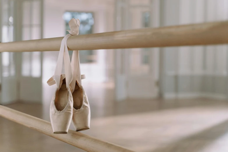 a pair of ballet shoes hanging on a rail, a picture, trending on unsplash, arabesque, balance beams, empty background, multiple stories, no - text no - logo