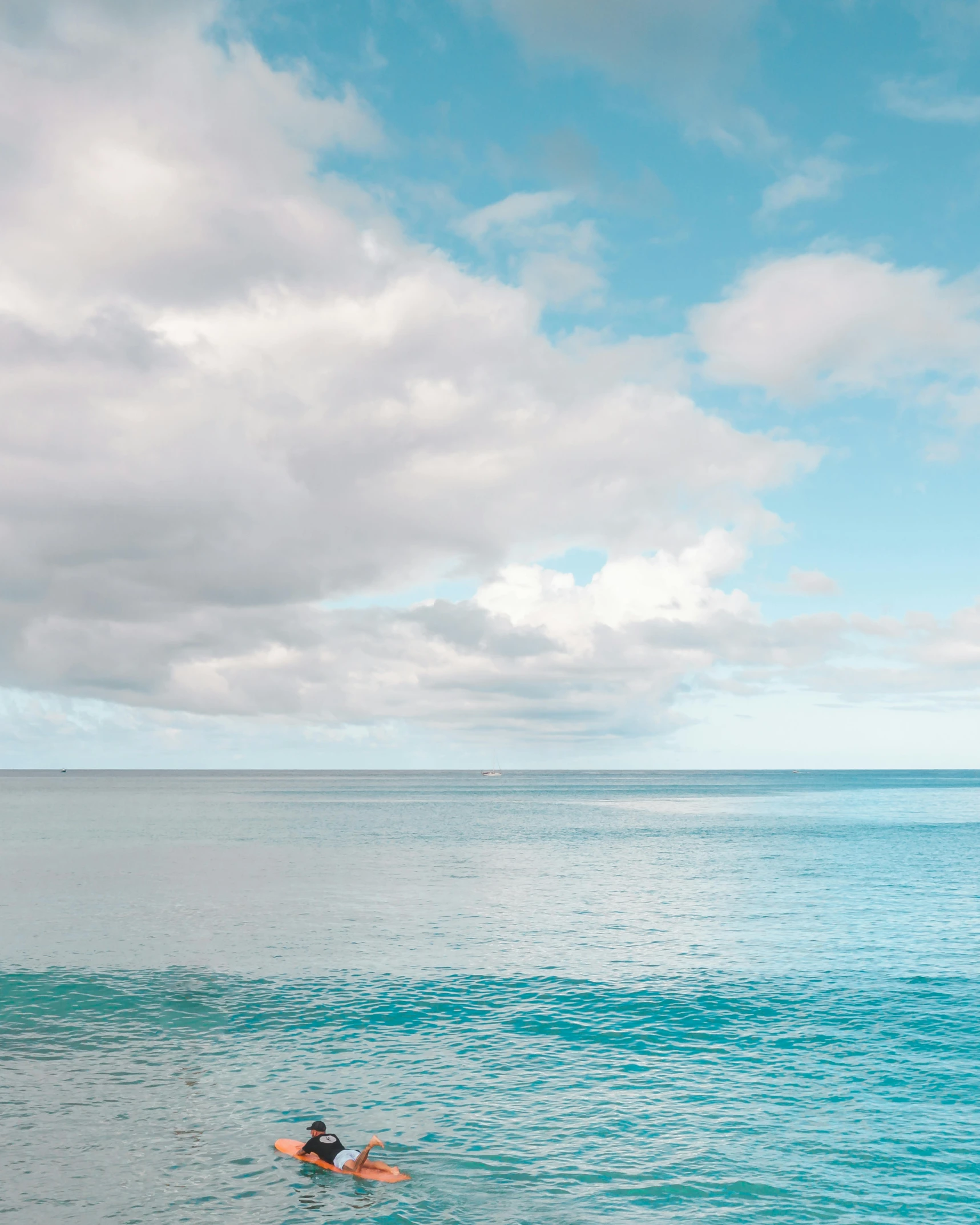 a person swimming in the ocean on a surfboard, clouds in the sky, ocean in the distance, cerulean blue, ( ( ( kauai ) ) )