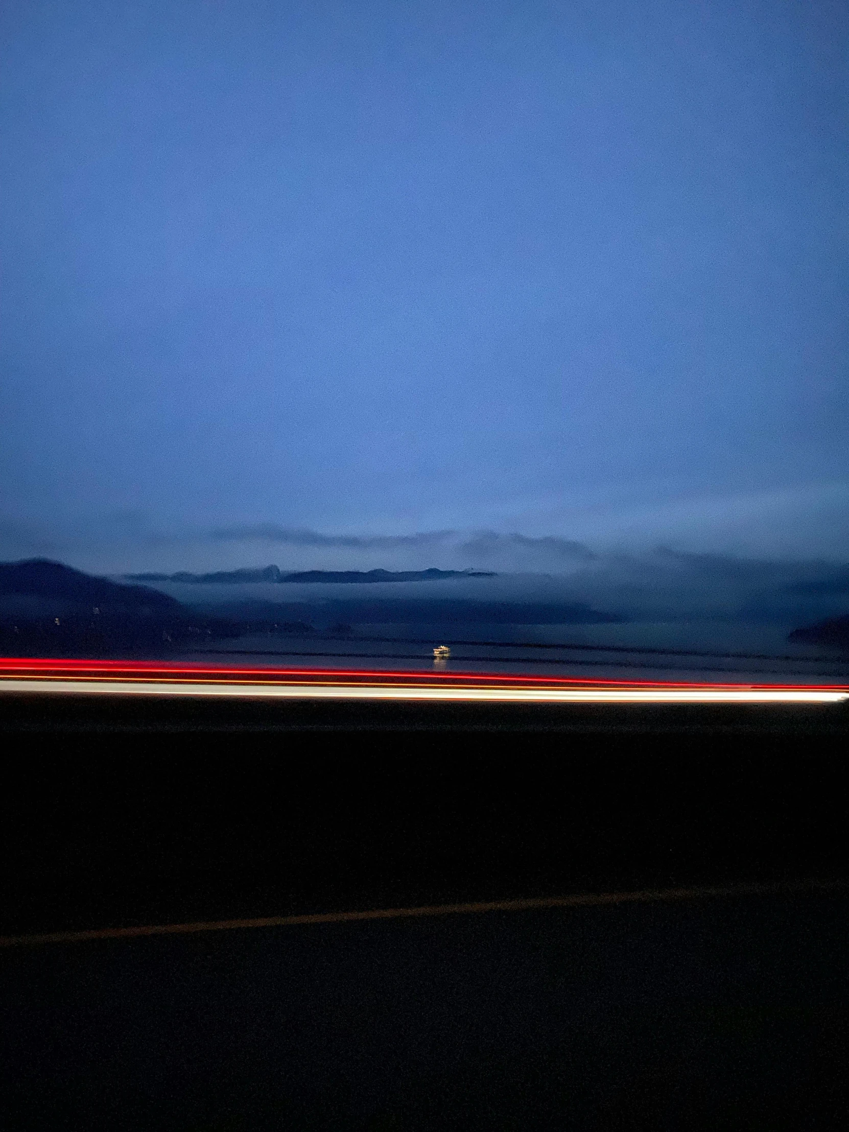 a car driving down a highway at night, a picture, inspired by Jan Rustem, postminimalism, ominous! landscape of north bend, blue and white and red mist, rebecca oborn, photograph taken in 2 0 2 0