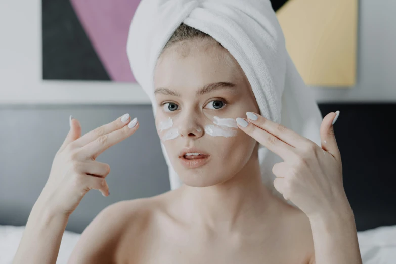 a woman with a towel on her head putting cream on her face, by Emma Andijewska, trending on pexels, square facial structure, bags under eyes, manuka, heart - shaped face