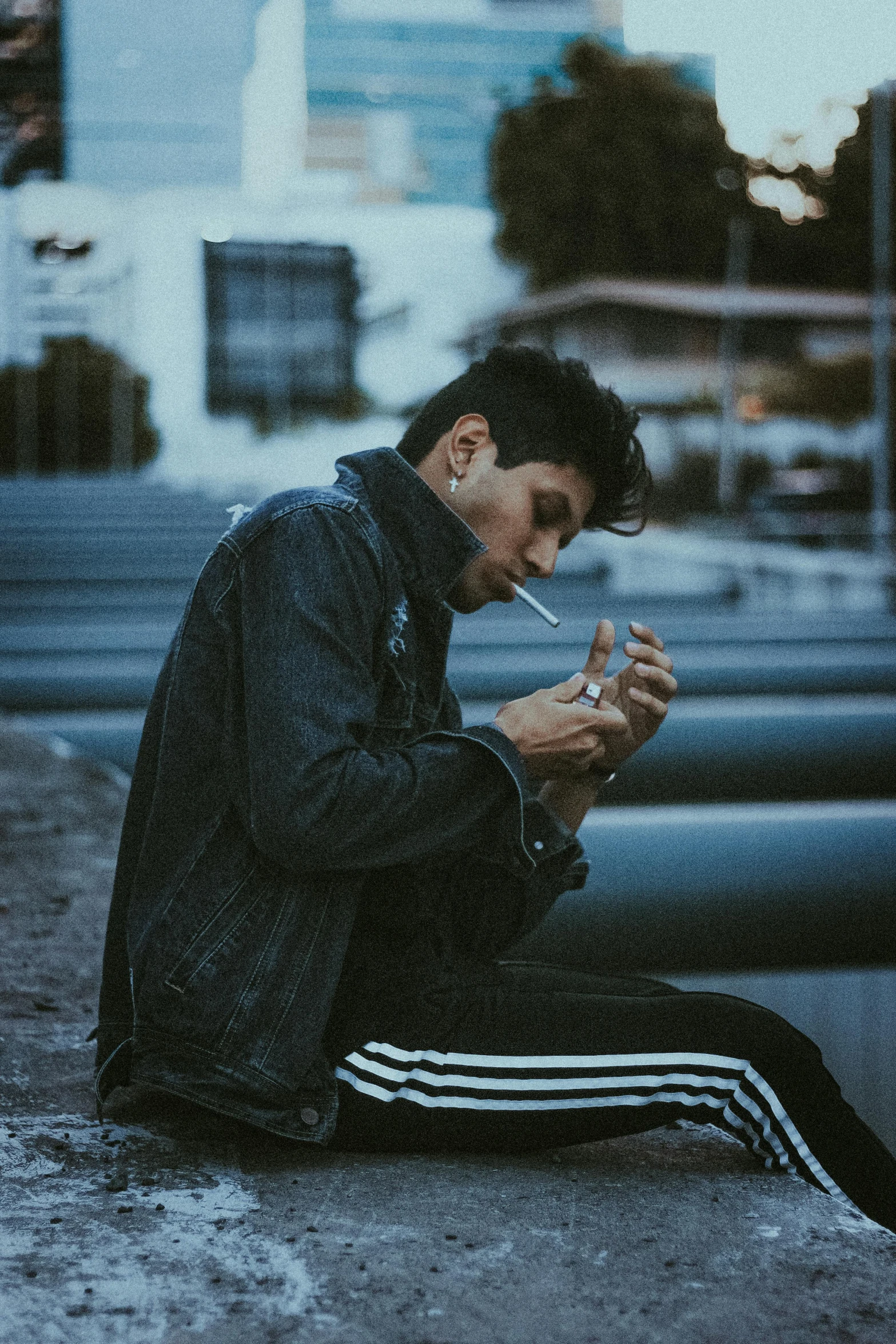 a man sitting on a ledge smoking a cigarette, pexels contest winner, realism, wearing a track suit, profile image, androgynous person, wearing a jeans jackets