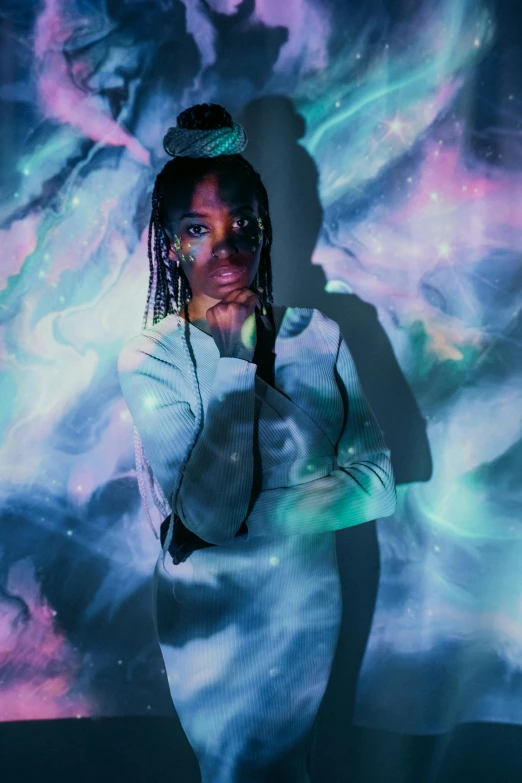 a woman with dreadlocks standing in front of a painting, an album cover, trending on pexels, afrofuturism, floatiung in front of a nebula, iridescent image lighting, black teenage girl, portrait mode photo