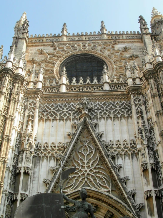 a large cathedral with a statue in front of it, inspired by Francisco de Burgos Mantilla, intricate scrollwork, seville, gothic arch frame, seen from outside