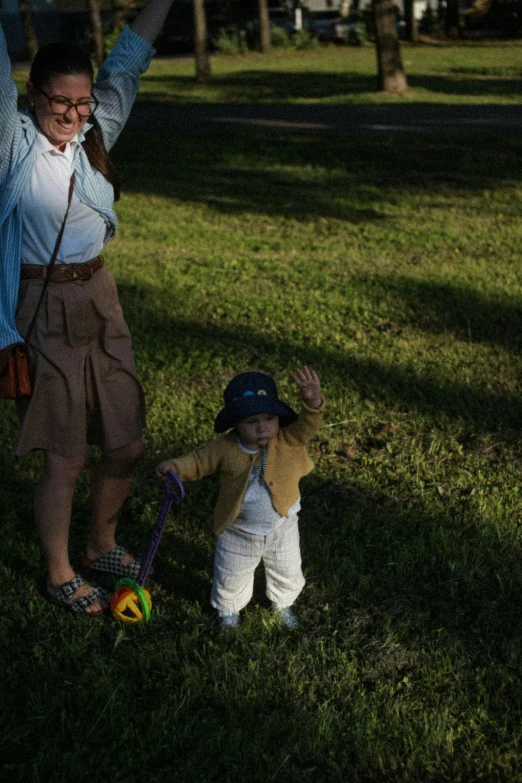 a woman and a child holding hands in a park, an album cover, by Sven Erixson, unsplash, holding a ball, baggy clothing and hat, low-light photograph, lawn