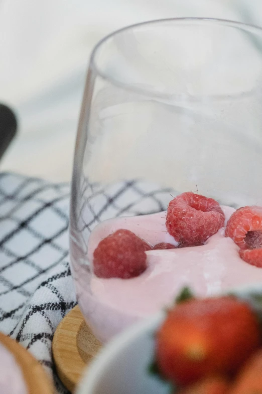 a glass filled with raspberries next to a bowl of strawberries, unsplash, yogurt, zoom shot, pink, holiday