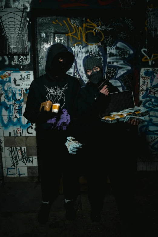 two people standing in front of a wall covered in graffiti, an album cover, by Daarken, reddit, wearing a dark hood, juice, cultist, (night)