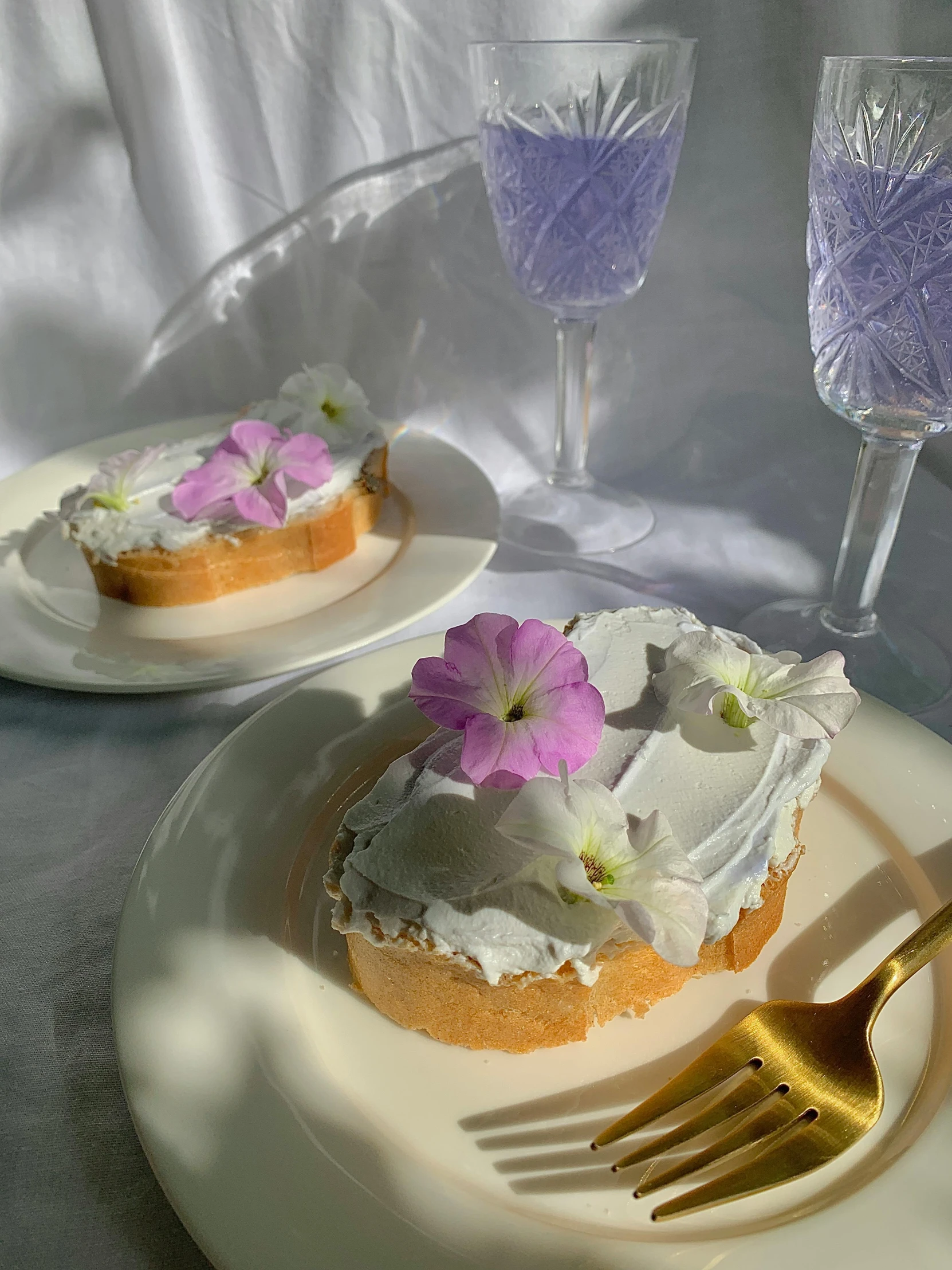 a white plate topped with a piece of cake next to a glass of wine, violet flowers, y2k aesthetic, background image, white stone arches