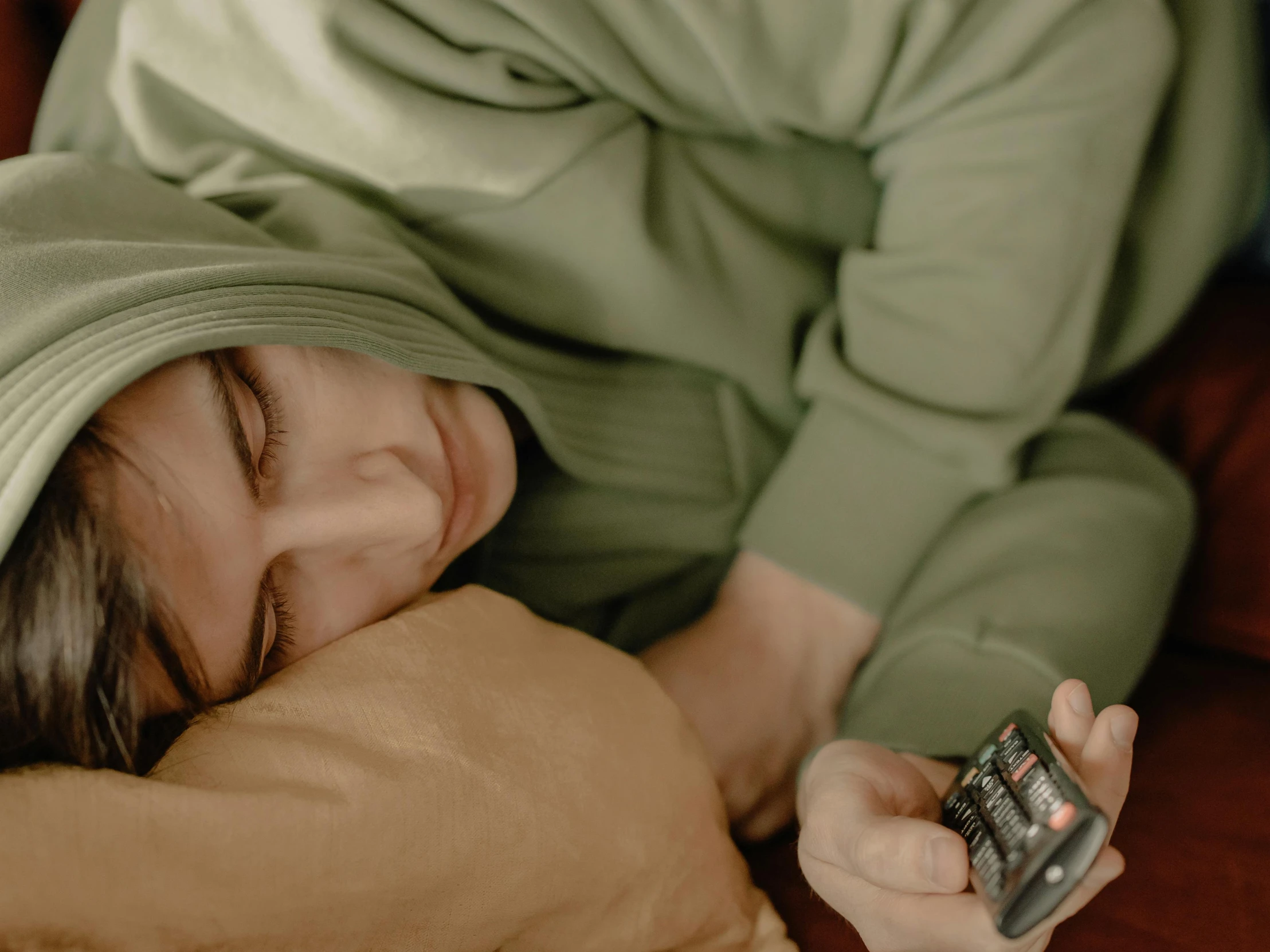 a woman laying on a couch holding a cell phone, trending on pexels, happening, wearing a green cloak, curled up under the covers, boy with neutral face, tv series