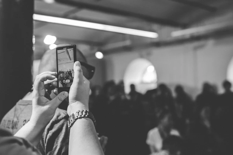 a black and white photo of a person taking a picture, happening, audience sorrounding, android cameraphone, information, uploaded