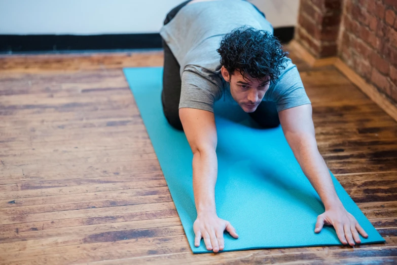 a man doing a yoga pose on a blue mat, by Rachel Reckitt, unsplash, working out, crawling, background image, high quality upload