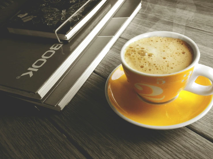 a cup of coffee sitting on top of a saucer, pexels contest winner, yellow hue, sitting on a mocha-colored table, like a catalog photograph, film photo