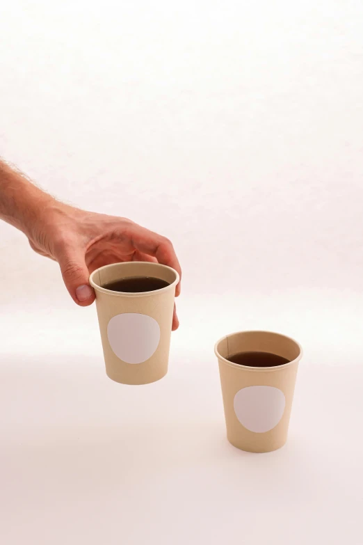 a person reaching for a cup of coffee, by Harvey Quaytman, circular cardboard eyes, official product photo, with two front pockets, wood cups