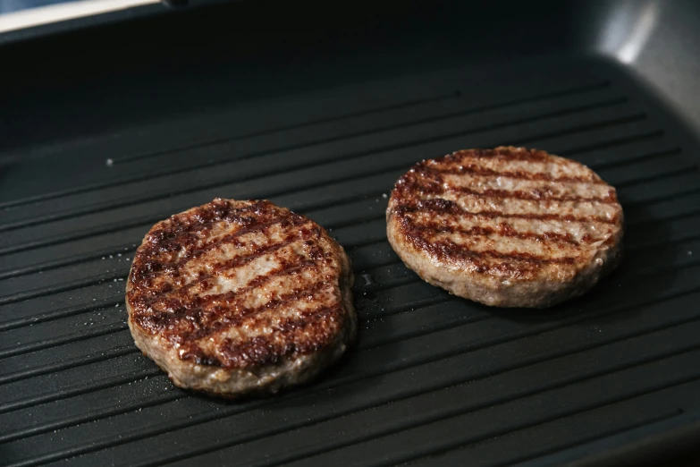 two hamburger patties are cooking on a grill, a hologram, unsplash, figuration libre, highly realistic. live cam, product image