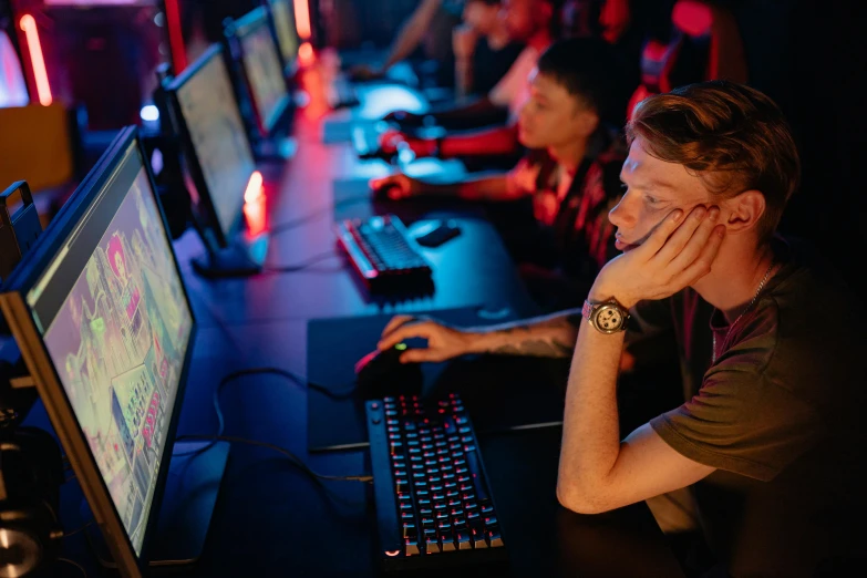 a man sitting in front of a computer on a desk, esports, looking distracted, red lighting on their faces, sierra entertainment games