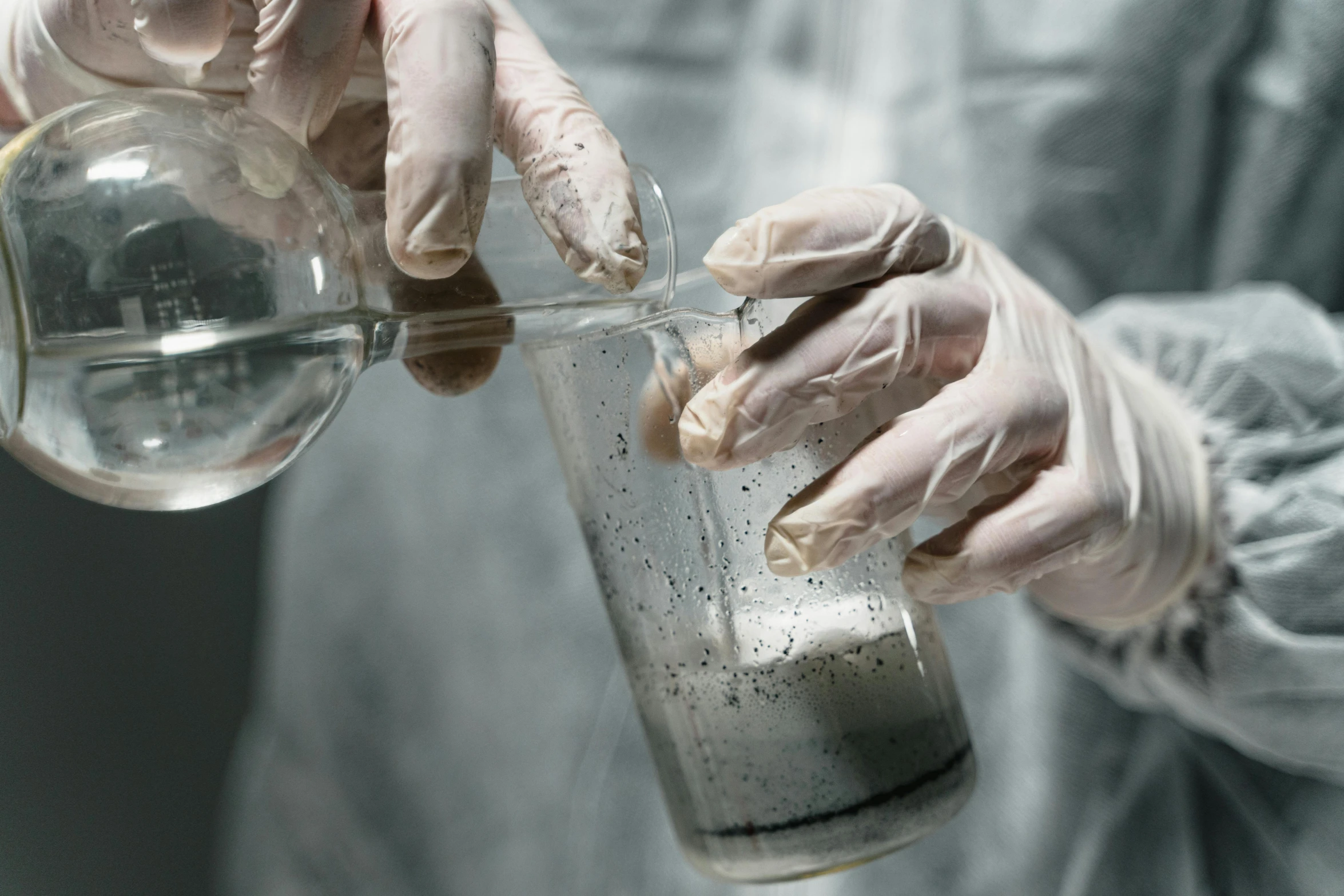 a person in a lab coat holding a beaker filled with liquid, unsplash, process art, wet concrete, grey, victorian alchemists, nitrogen-rich soil