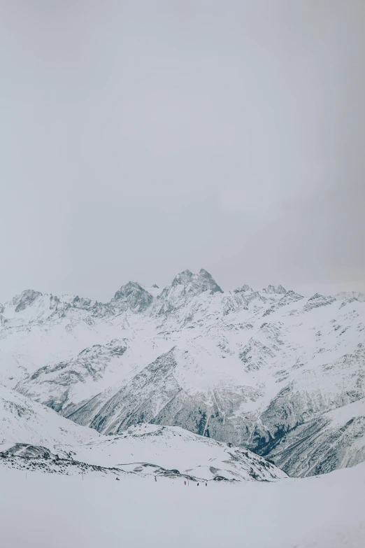 a man riding a snowboard down the side of a snow covered slope, trending on pexels, distant mountain range, gray sky, stacked image, photo of zurich