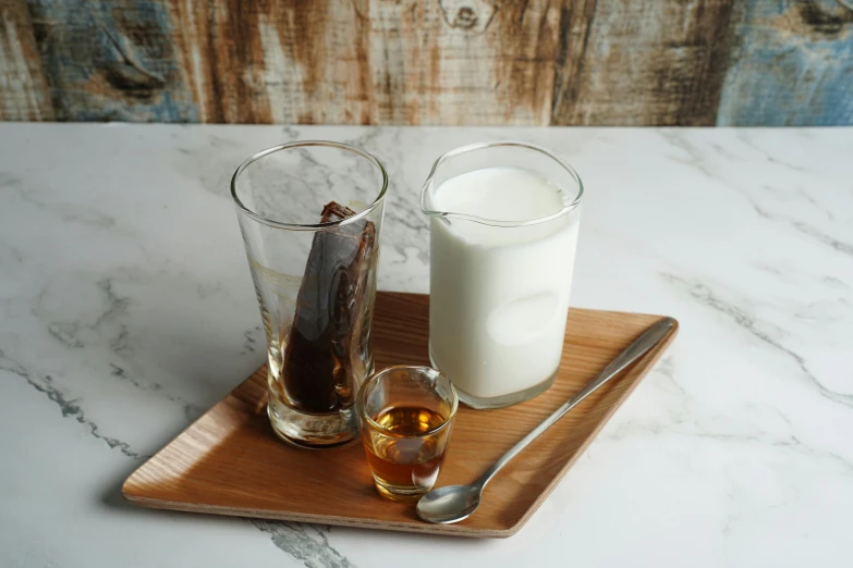 a couple of glasses sitting on top of a wooden tray, inspired by Joseph Beuys, milk and mocha style, caramel, plated arm, long