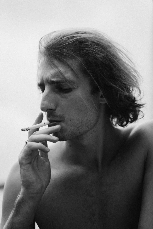 a black and white photo of a man smoking a cigarette, inspired by Antonin Artaud, reddit, mid long hair, profile image, young man, will graham