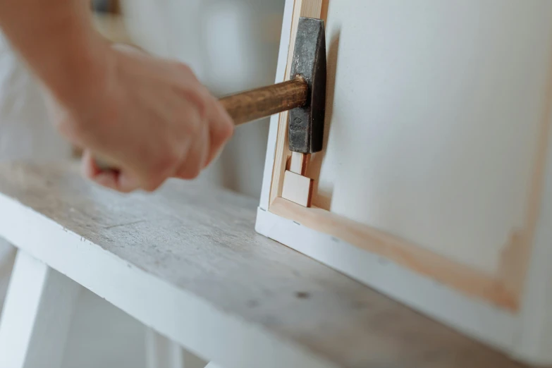 a person that is holding a hammer in their hand, pexels contest winner, arts and crafts movement, wooden trim, white finish, shelf, square shapes