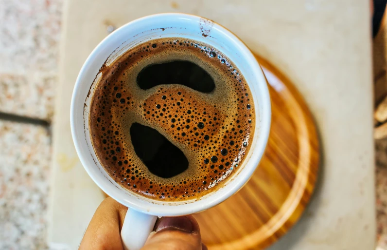 a close up of a person holding a cup of coffee, by Julia Pishtar, pexels contest winner, hurufiyya, made of ferrofluid, a wooden, turkey, :: morning