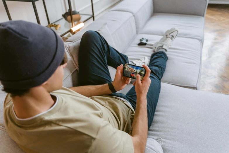 a man sitting on a couch playing a video game, a picture, by Adam Marczyński, trending on pexels, style game square enix life, jeans and t shirt, smartphone photo, sage ( valorant )