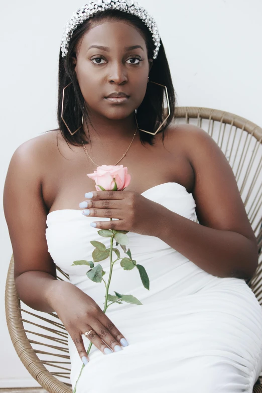 a woman sitting in a chair with a rose in her hand, an album cover, by Lily Delissa Joseph, unsplash, in a maxi white dress, light brown skin, holding a rose in a hand, casual pose