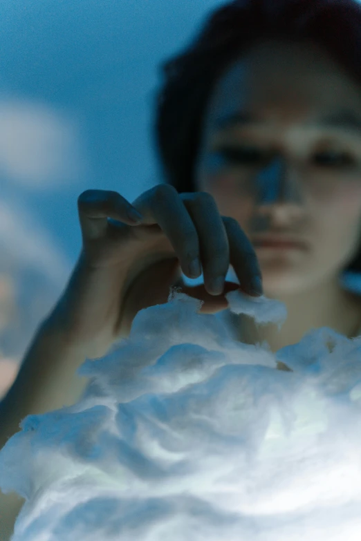 a woman that is holding something in her hand, a marble sculpture, inspired by Fei Danxu, unsplash, video art, cotton clouds, soft bioluminescent membranes, cinematic closeup, frozen