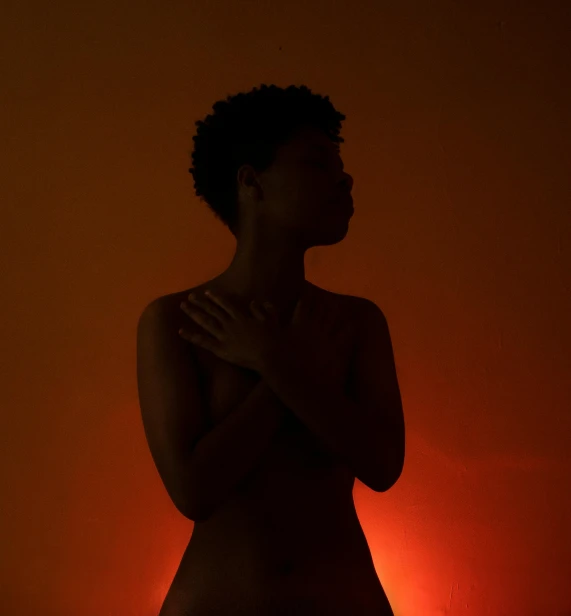 a woman standing in front of a red light, an album cover, inspired by Carrie Mae Weems, pexels contest winner, symbolism, beautiful female body silhouette, orange yellow ethereal, dark. studio lighting, medium format. soft light