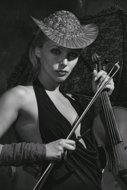a black and white photo of a woman holding a violin, an album cover, inspired by Gyula Basch, woman with hat, (fantasy), sergey krasovskiy, gorgeous stella maeve magician