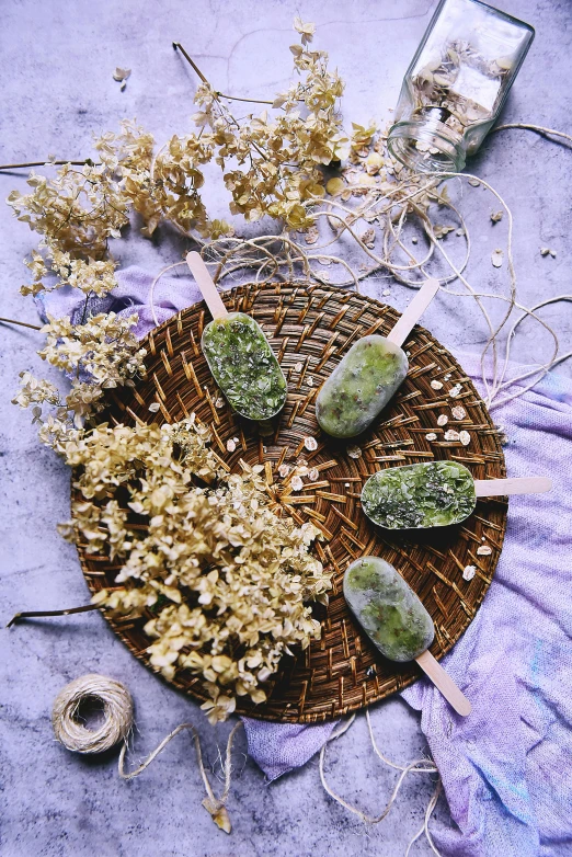 a basket of dried flowers sitting on top of a table, ice cream, mossy stone, flatlay, green