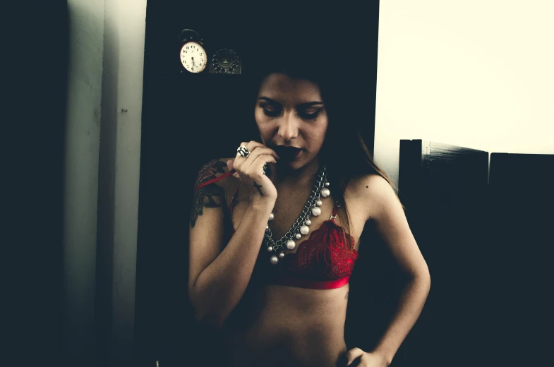 a woman taking a picture of herself in a mirror, a photo, inspired by Elsa Bleda, tumblr, tachisme, red bra, wearing a bandana and chain, colombian, dark tone