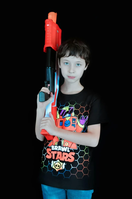 a young boy holding a red and black toy gun, inspired by Otto Stark, rainbow coloured rockets, standing with a black background, a laser rifle, black shirt with red star