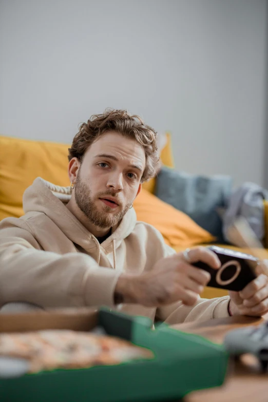 a man sitting on a couch holding a remote control, by artist, trending on pexels, renaissance, twitch streamer / gamer ludwig, serious expression, pete davidson, morning time