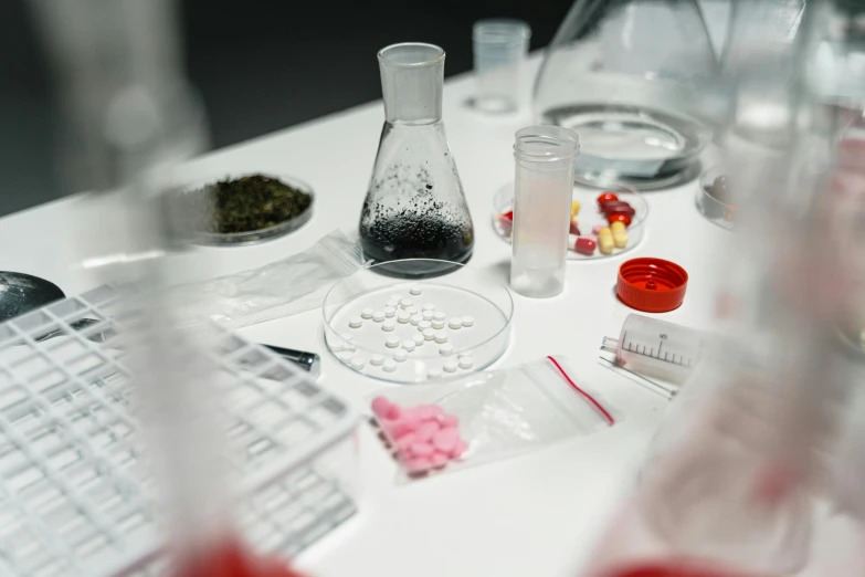 a group of laboratory equipment sitting on top of a white table, a picture, by Adam Marczyński, candy treatments, thumbnail, contain, pills