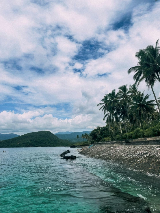 a body of water surrounded by palm trees, by Robbie Trevino, sumatraism, hills and ocean, background image, multiple stories, thumbnail