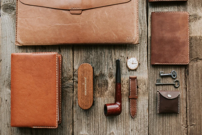 a leather case sitting on top of a wooden table, a still life, inspired by Harrington Mann, trending on unsplash, various sizes, fine pen, tan, vintage - w 1 0 2 4