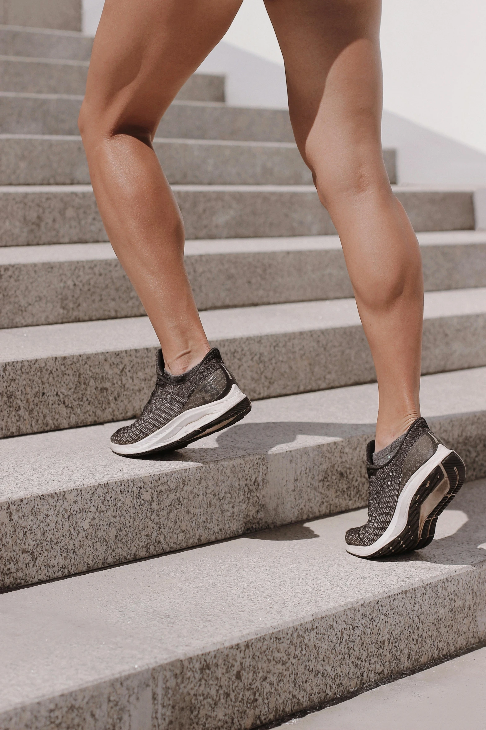 a woman running up a flight of stairs, in gunmetal grey, rubber waffle outsole, grey metal body, body format