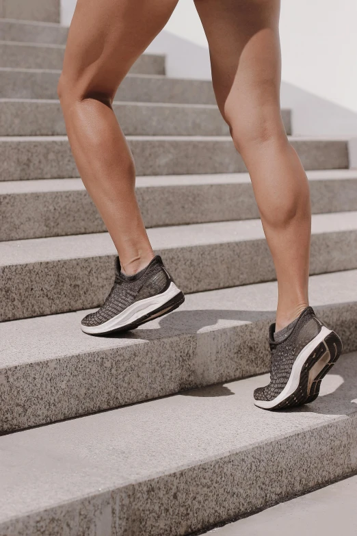 a woman running up a flight of stairs, in gunmetal grey, rubber waffle outsole, grey metal body, body format