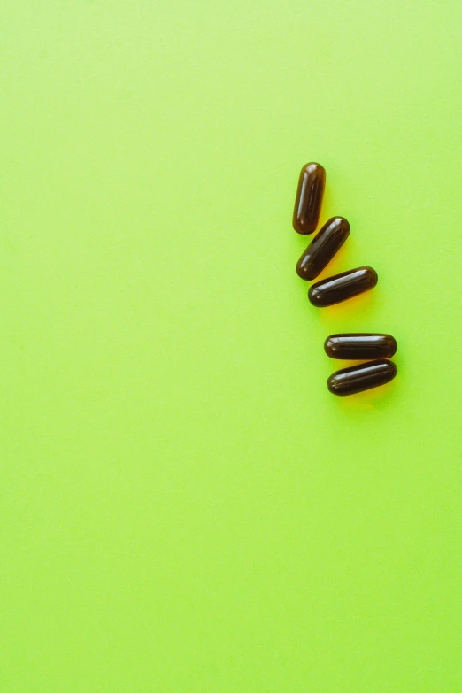 a couple of pills sitting on top of a green surface, by Julia Pishtar, antipodeans, chocolate, bright green dark orange, exponential, vine