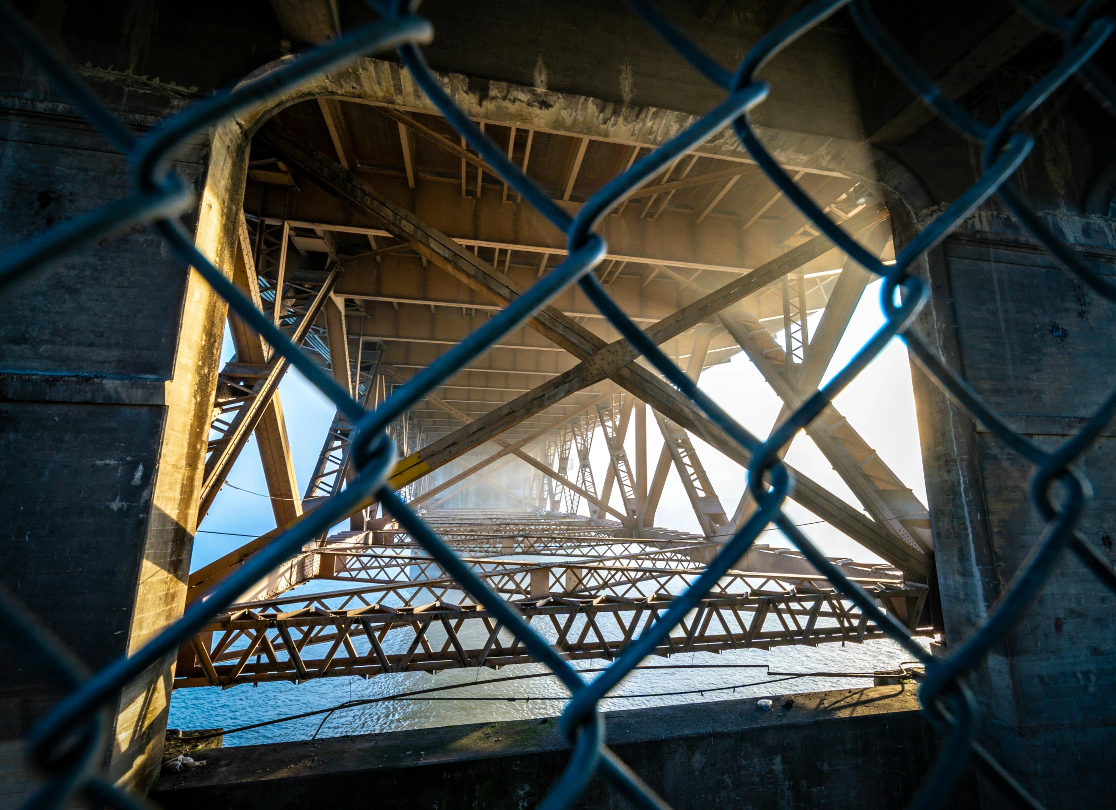 a view of a bridge through a chain link fence, by Matt Stewart, unsplash contest winner, graffiti, hell gate, lookout tower, full frame, brown