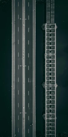 a black and white photo of a highway, by Jacob Toorenvliet, unsplash contest winner, conceptual art, knolling, two towers, bridge over the water, color aerial photo drone