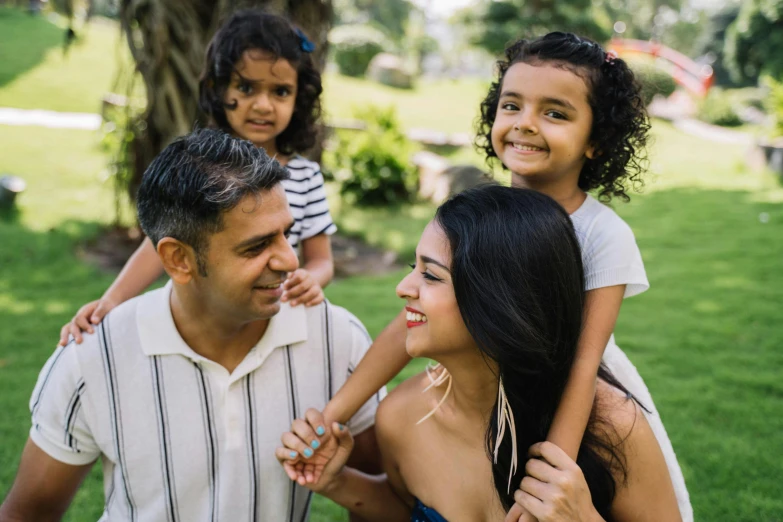 a young girl sitting on top of a man's shoulders, pexels contest winner, hurufiyya, of a family standing in a park, indian girl with brown skin, husband wife and son, avatar image