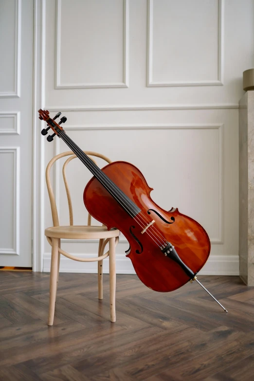 a cello sitting on top of a wooden chair, sitting on a chair, sitting on a stool