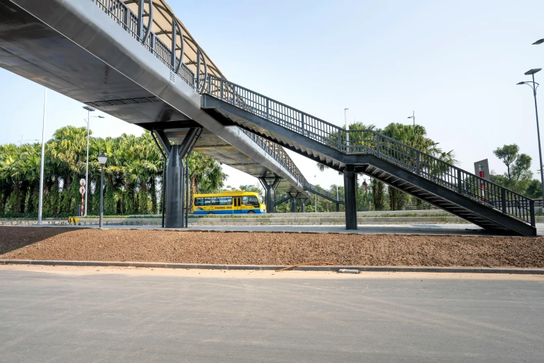a train that is going under a bridge, unsplash, bauhaus, futuristic phnom-penh cambodia, bus station, outdoor staircase, laquer and steel