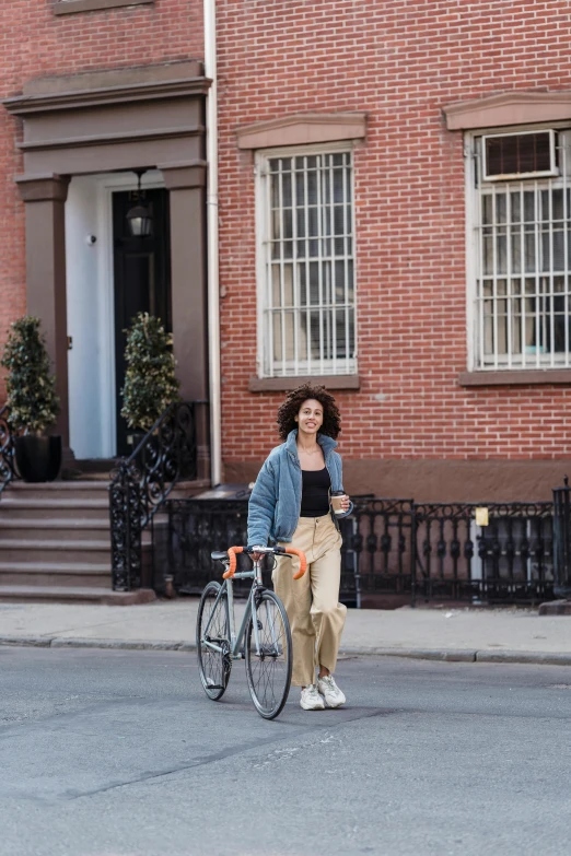 a woman walking her bike down the street, by Nina Hamnett, happening, curly haired, brooklyn, abcdefghijklmnopqrstuvwxyz, gaspar peeter